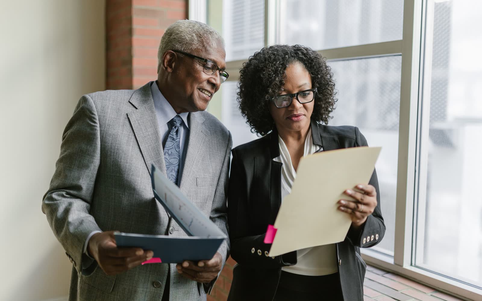 Two colleagues reviewing documents together in a bright office